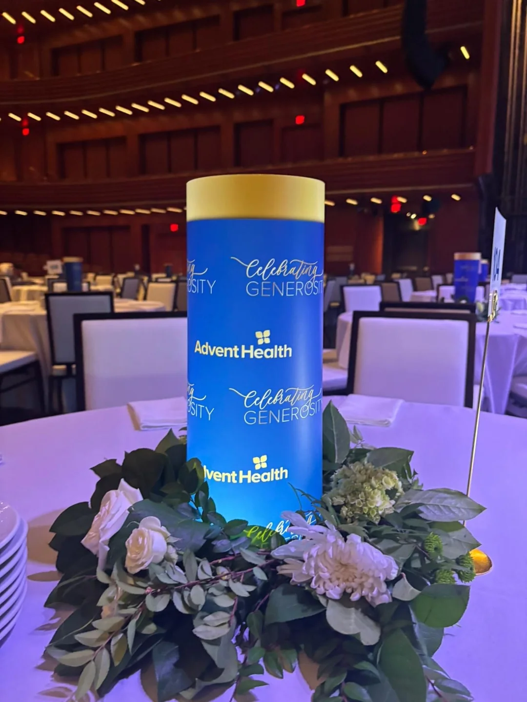 A branded illuminated centerpiece surrounded by place settings and candles